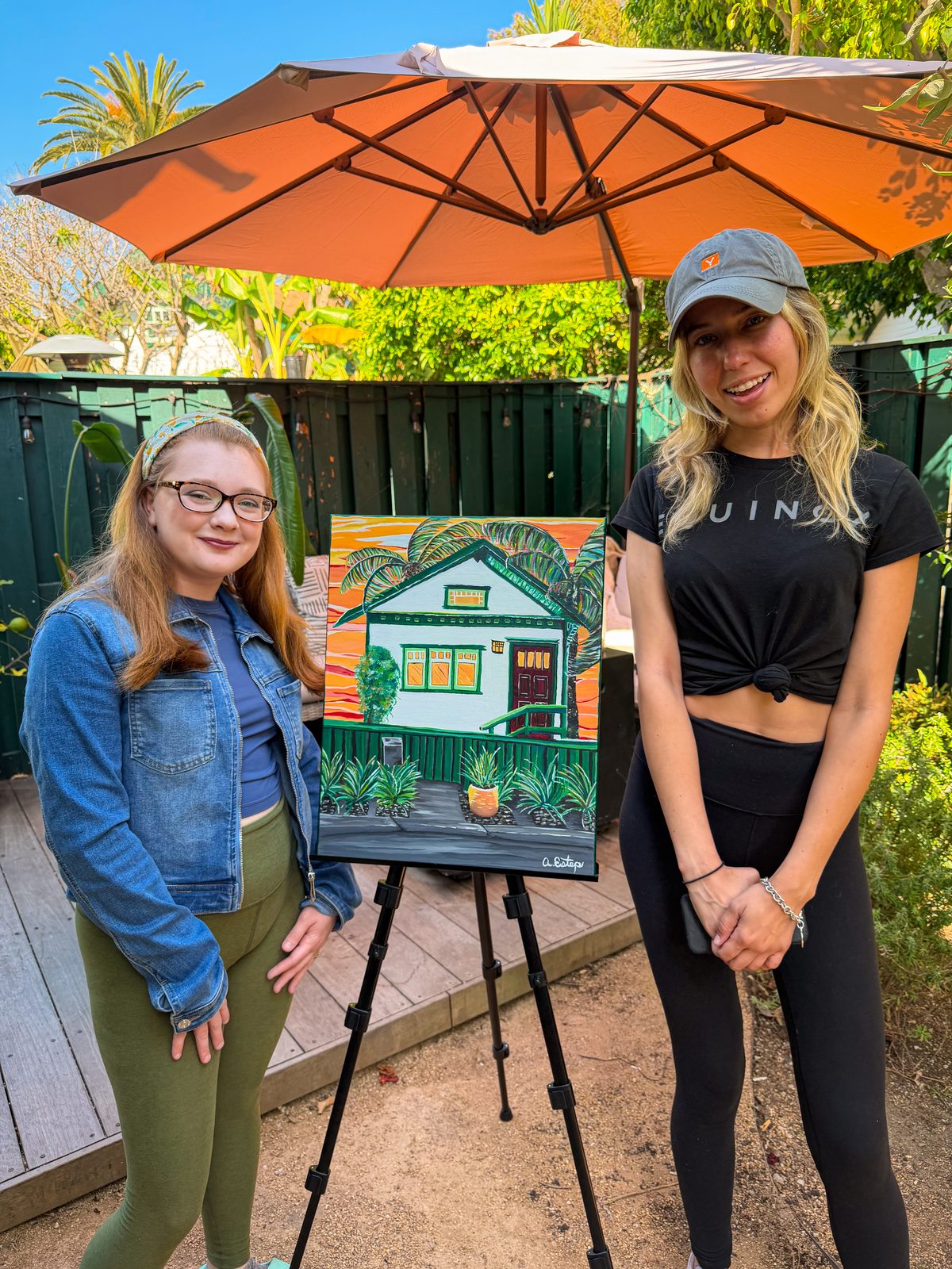 The garden studio — Andrea and a collector with a finished painting on the easel, under the big umbrella